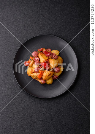 Grilled potatoes cut into slices with hunting sausages with garlic, onion Grilled potatoes cut into slices with hunting sausages with garlic, onion 113754286