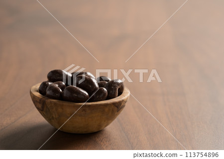 Chocolate covered cashew nuts in a bowl on wood table Chocolate covered cashew nuts in a bowl on wood table 113754896