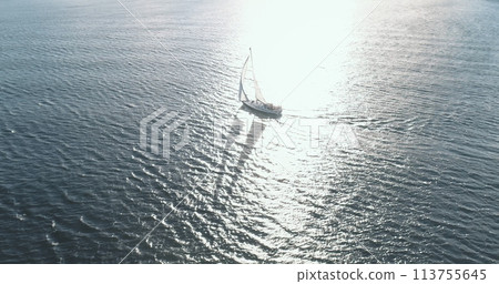 Slow motion of sailing yacht at sun reflect ocean gulf. Aerial view of luxury boat reflection. Sailboat regatta at open sea. Epic seascape at summer cruise at Arran Island, Scotland, Europe 113755645