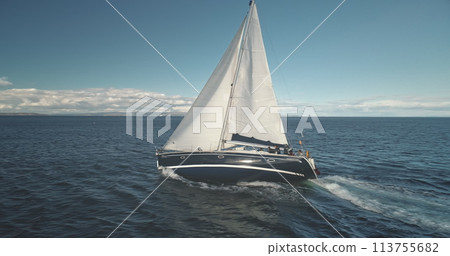 Slow motion closeup of sail luxury yacht at ocean bay aerial. Boat race at open sea. Sailboat regatta at Brodick harbor, Arran Island, Scotland, Europe. Seascape with sun reflection at summer cruise 113755682