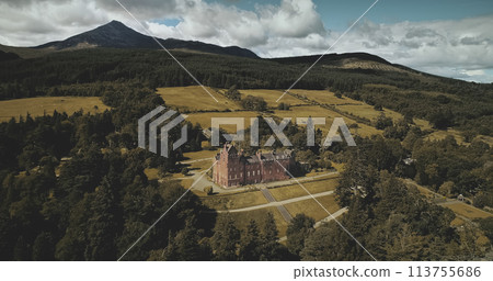 Scotland ocean coast landscape aerial view: forests, valleys, hills. Brodick castle - historical ancient building in Arran Island. Road with riding cars. 113755686
