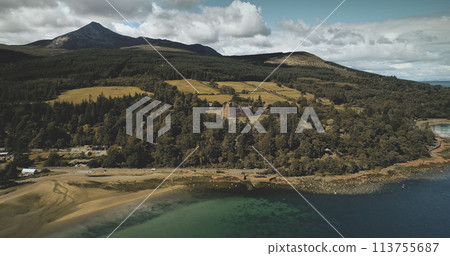 Scotland's ocean coast landscape aerial view: forests, valleys, hills. Brodick castle - historical ancient building in Arran Island. Road with riding cars shot 113755687