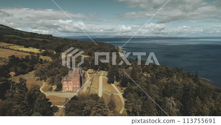 Scotland landscape, medieval castle aerial view: trees and ocean shore at Brodick Bay, Arran Island. Majestic scenery of green leafy wood at coastline. Beauty of Scottish nature. Cinematic shot 113755691