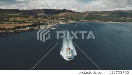 Scotland ocean, passenger ferry aerial view in coastal water of Firth-of-Clyde Gulf. Ship crossing from Brodick terminal to Scottish mainland. Cityscape at green valleys. Cinematic shot 113755700