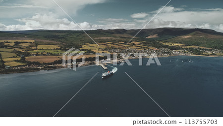 Scotland, Brodick Ferry Terminus aerial panoramic shot of ship crossing, Arran Island. Beautiful passenger ferry go from harbor at Firth-of-Clyde Gulf to mainland. Cinematic scenery view 113755703