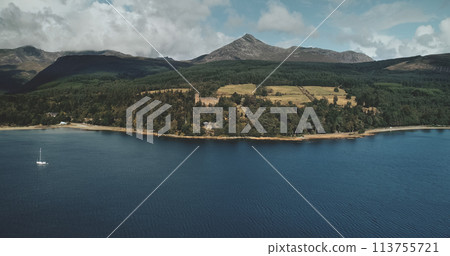 Scotland mountain Goatfell landscape aerial panoramic view at Brodick Harbour, Arran Island. Majestic Scottish nature scenery of forests, meadows and medieval castle. Scotland mountain Goatfell landscape aerial panoramic view at Brodick Harbour, Arran Island. Majestic Scottish nature scenery of forests, meadows and medieval castle. 113755721