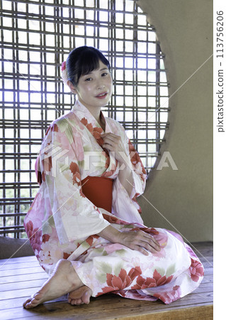 A woman in a yukata relaxing in a gazebo 113756206