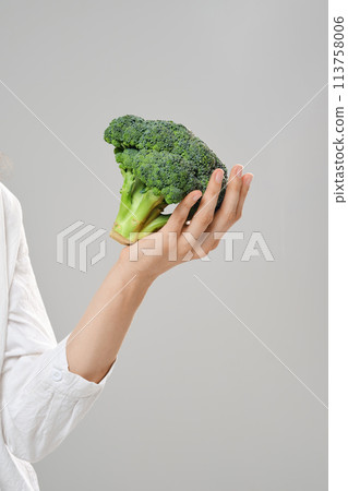 Healthy eating concept. Broccoli on female hand Healthy eating concept. Broccoli on female hand 113758006