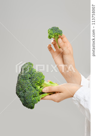 Unrecognizable woman tore a sprig of broccoli from the stem 113758007