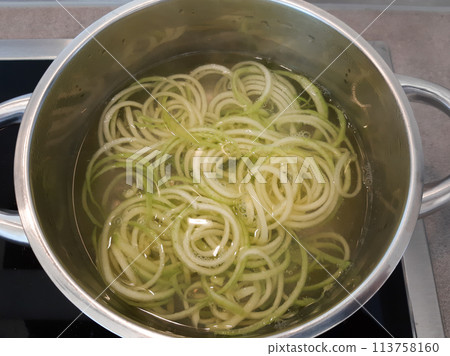 Curls of zucchini in the pot. Boiled vegetables, zucchini in a pan in hot water for blanching 113758160