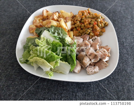 Homemade grilled chicken with french fries, green salad and pea stew served on a white plate 113758198