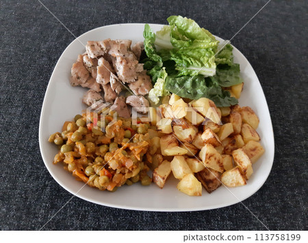 Homemade grilled chicken with french fries, green salad and pea stew served on a white plate 113758199