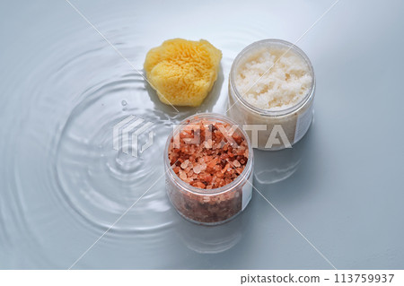 Body scrub, bath salt and natural sponge on a blue background with water. 113759937