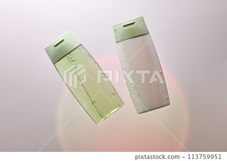 Shampoo and hair conditioner in water on a white background with colored light. Shampoo and hair conditioner in water on a white background with colored light. 113759951