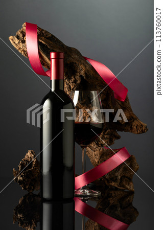 Bottle and glass of red wine on a black reflective background. 113760017