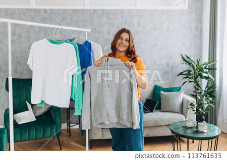 Beautiful attractive woman choosing clothes on clothes rack. Female Clothes on Open Clothes Rail. Selection of a wardrobe, stylist, shopping. 113761635