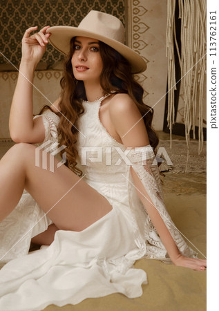 Beautiful girl posing in a boho style wedding dress Beautiful girl posing in a boho style wedding dress 113762161