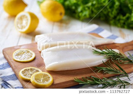 Raw squid and ingredients on white wooden table with lemon and herbs.  Fresh seafood concept. 113762727