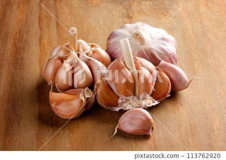 Close Up Raw, Fresh Garlic Cloves and Bulbs on Rustic Wooden Table 113762920