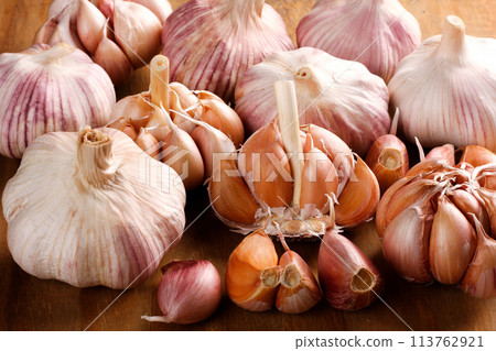 Close Up Raw, Fresh Garlic Cloves and Bulbs on Rustic Wooden Table Close Up Raw, Fresh Garlic Cloves and Bulbs on Rustic Wooden Table 113762921