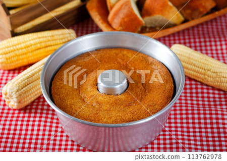 corn cake in the pan baking form on rustic wooden table. Typical Brazilian party food. Selective focus corn cake in the pan baking form on rustic wooden table. Typical Brazilian party food. Selective focus 113762978
