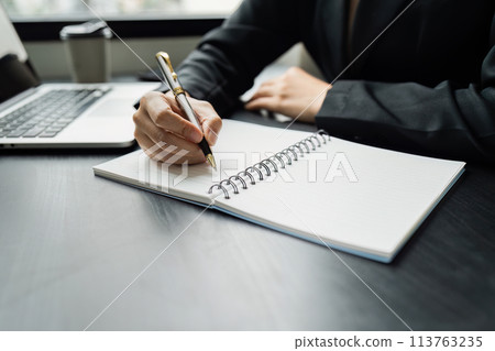 Business woman working in office writing plan on note book and use computer laptop meeting online 113763235