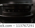 Closeup of camera lens aperture scale, engraved depth of field numbers, precise focus control for photography, black textured background 113767291