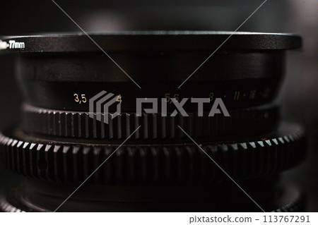 Closeup of camera lens aperture scale, engraved depth of field numbers, precise focus control for photography, black textured background Closeup of camera lens aperture scale, engraved depth of field numbers, precise focus control for photography, black textured background 113767291
