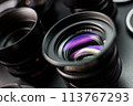 Vivid reflection on the glass of a vintage MC lens, detailed view of photographic collection, lenses in soft focus in the background 113767293