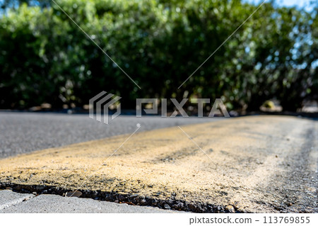 Selective focus on area in front of a asphalt speed bump . Selective focus on area in front of a asphalt speed bump . 113769855