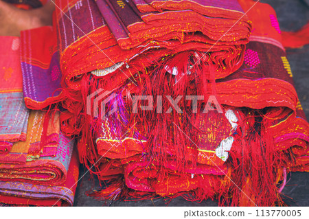 Close up to a stack of vibrant red Ulos fabric showcasing indigenous ethnic design showing the authentic culture and heritage of the Batak people from North Sumatra Indonesia Close up to a stack of vibrant red Ulos fabric showcasing indigenous ethnic design showing the authentic culture and heritage of the Batak people from North Sumatra Indonesia 113770005