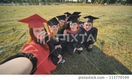 College alumni take selfies in the meadow. 113770599