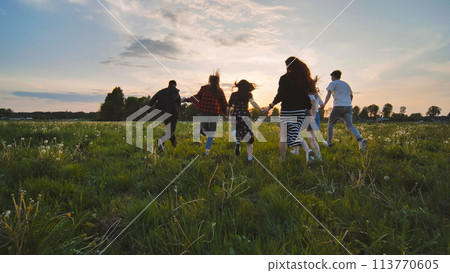 Merry friends run off into the sunset holding hands. Merry friends run off into the sunset holding hands. 113770605