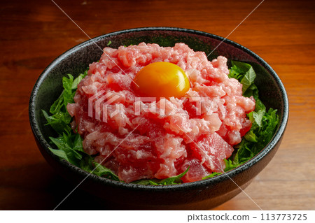 Negitoro seafood bowl with egg yolk and perilla leaves, overhead view Negitoro seafood bowl with egg yolk and perilla leaves, overhead view 113773725