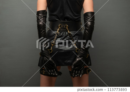 Beautiful young woman in a leather dress and bondage set posing back Beautiful young woman in a leather dress and bondage set posing back 113773893