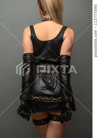 Beautiful young woman in a leather dress and bondage set posing back Beautiful young woman in a leather dress and bondage set posing back 113773898