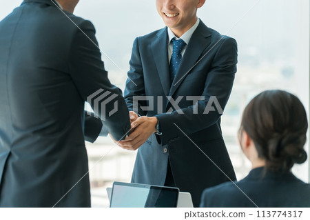 商人在公司辦公室/會議室握手並簽訂合約 商人在公司辦公室/會議室握手並簽訂合約 113774317