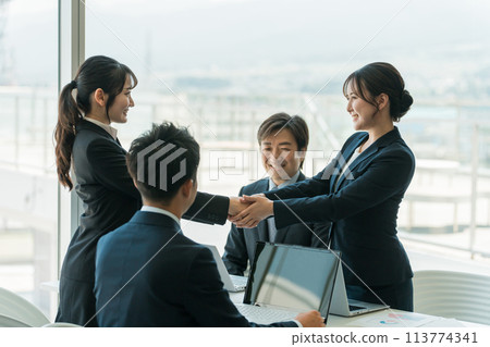 Businesswomen shaking hands to close a deal in a corporate office/conference room 113774341