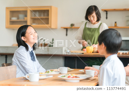一個穿著制服的國中女孩在早餐桌上微笑著與弟弟交談 一個穿著制服的國中女孩在早餐桌上微笑著與弟弟交談 113774491