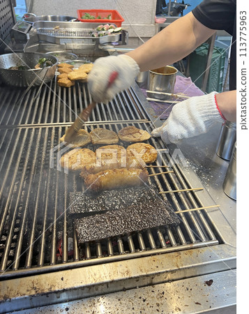 Photographing a barbecue vendor applying barbecue sauce to the barbecue 113775963