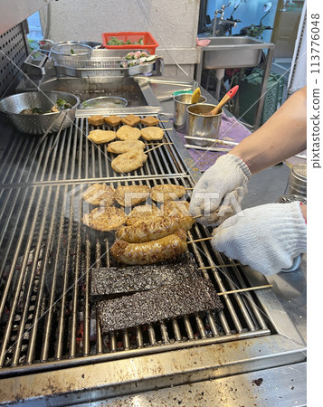 Photographing a barbecue vendor flipping the barbecue and cooking it 113776048