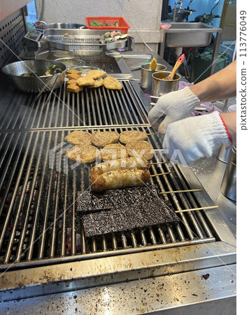 拍攝販賣燒烤的攤販正在為燒烤翻面烤熟 113776049