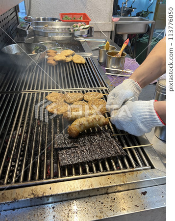 拍攝販賣燒烤的攤販正在為燒烤翻面烤熟 113776050