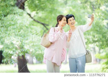 Middle-aged woman taking a selfie in a park with fresh greenery Tourism Women's trip Middle-aged woman taking a selfie in a park with fresh greenery Tourism Women's trip 113776271