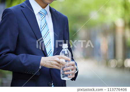 Business image: A young man in a suit holding a plastic bottle Business image: A young man in a suit holding a plastic bottle 113776406