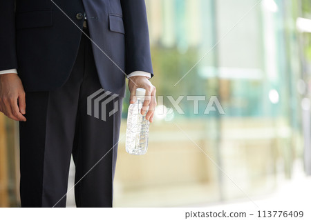 Business image: A young man in a suit holding a plastic bottle Business image: A young man in a suit holding a plastic bottle 113776409