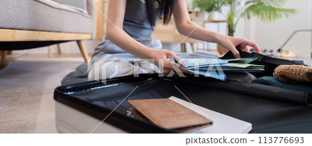 Young woman packing suitcase at home. Travel concept 113776693