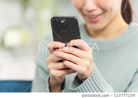 在客廳裡操作智能手機的女人 113777159