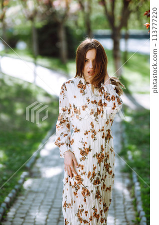 Beautiful young woman near the blooming spring tree. Attractive girl enjoying her time outside in park. Beautiful young woman near the blooming spring tree. Attractive girl enjoying her time outside in park. 113777220