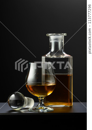 Old decanter and glass with whiskey, cognac or brandy. Old decanter and glass with whiskey, cognac or brandy. 113777296